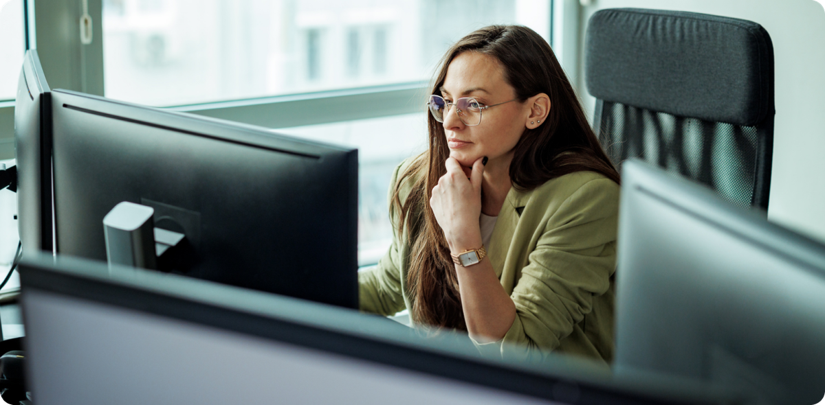 Focused woman at desk with multiple monitors, reflecting how AI change is reshaping the financial services frontline.