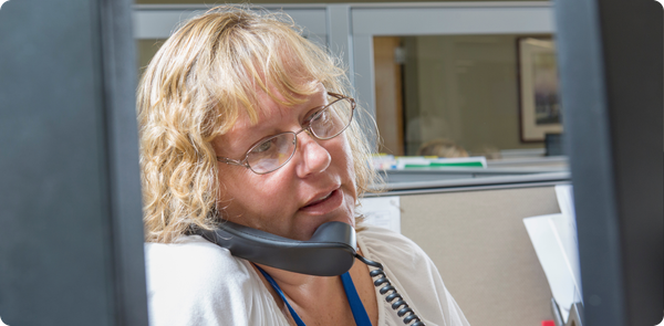 Stressed employee on phone in office cubicle, capturing the urgency of building frontline resilience during disruption