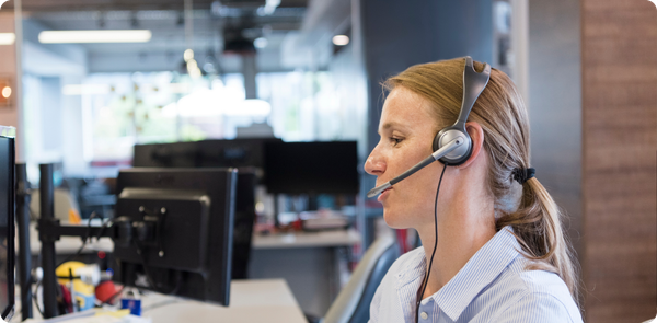 Focused call center agent using headset and desktop computer, showing skills used to boost first-call resolution