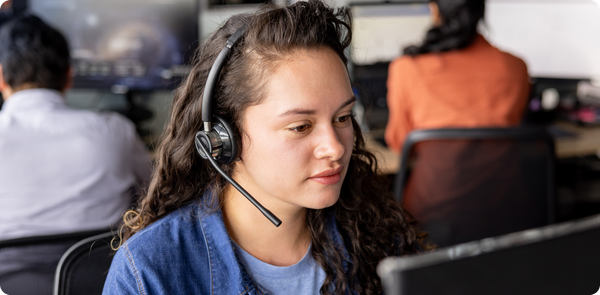 Woman with headset focused on screen, representing engaged frontline employee boosting customer satisfaction
