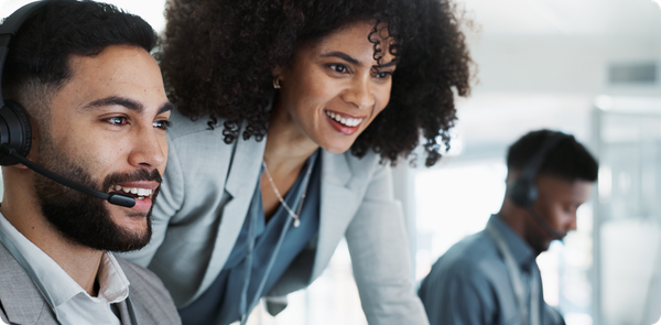 Smiling call center agent wearing a headset receives support from a manager, symbolizing trust, coaching, and readiness for AI integration on the frontline