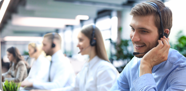 Smiling customer service representatives wearing headsets in a bright call center, illustrating the impact of strong employee retention strategies