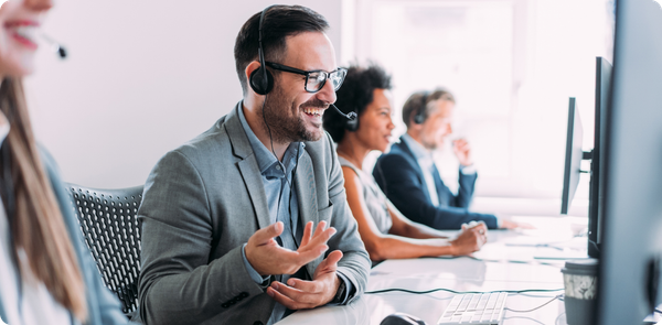 Smiling team leader coaching peers at computers, showing support needed to avoid change management failure