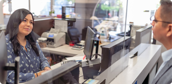 Universal banker assisting a customer at a branch desk, showing personalized service that connects branch and digital experiences.