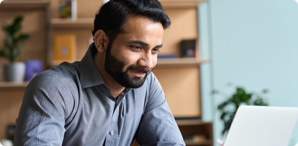 Smiling team leader working on a laptop, symbolizing confidence and calm while navigating uncertainty in the workplace.