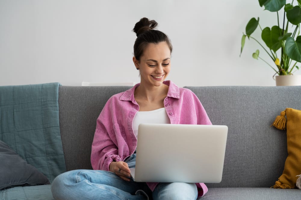 womans smiling and using a laptop - How to Make Fake Text Message Video