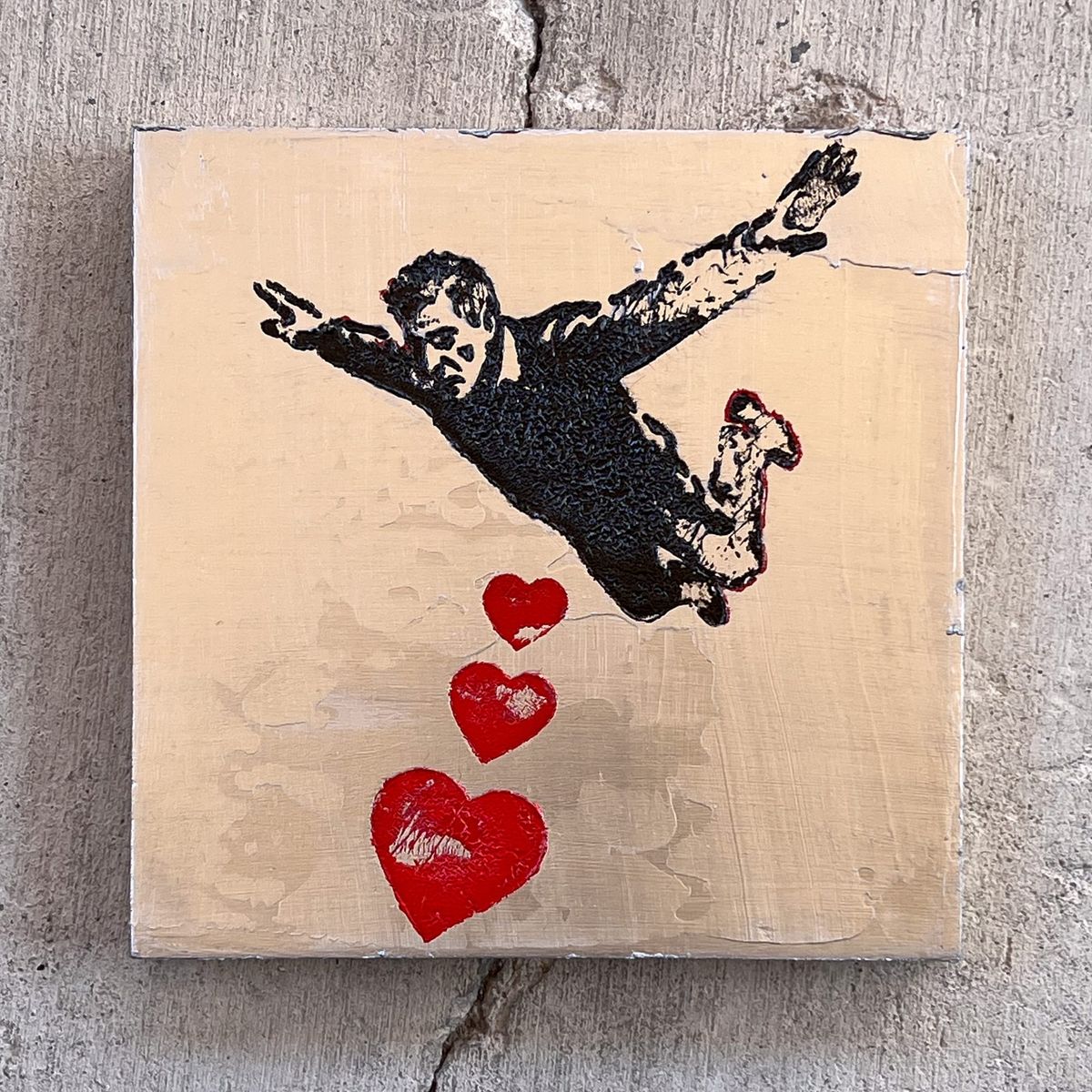 Silver painting with black figure in free fall and red hearts on a metallic ground, stark graphic contrast between elements.