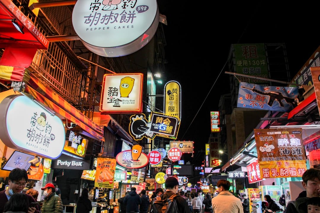 Crowds and lit food stalls at a Taipei night market after dark