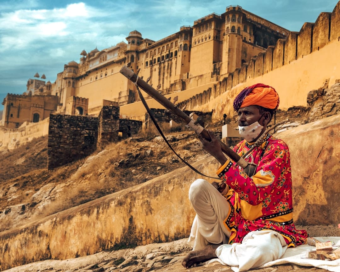 Amber Fort rising above the hillside near Jaipur with a Rajasthani musician in the foreground