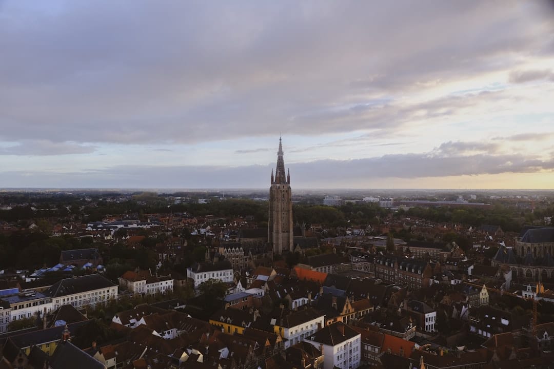 The tall brick spire of the Church of Our Lady rising above the rooftops of Bruges at dusk