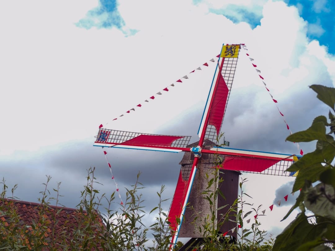 A wooden windmill with red sails and a Flemish lion flag on the Kruisvest ramparts in the Sint-Anna quarter of Bruges