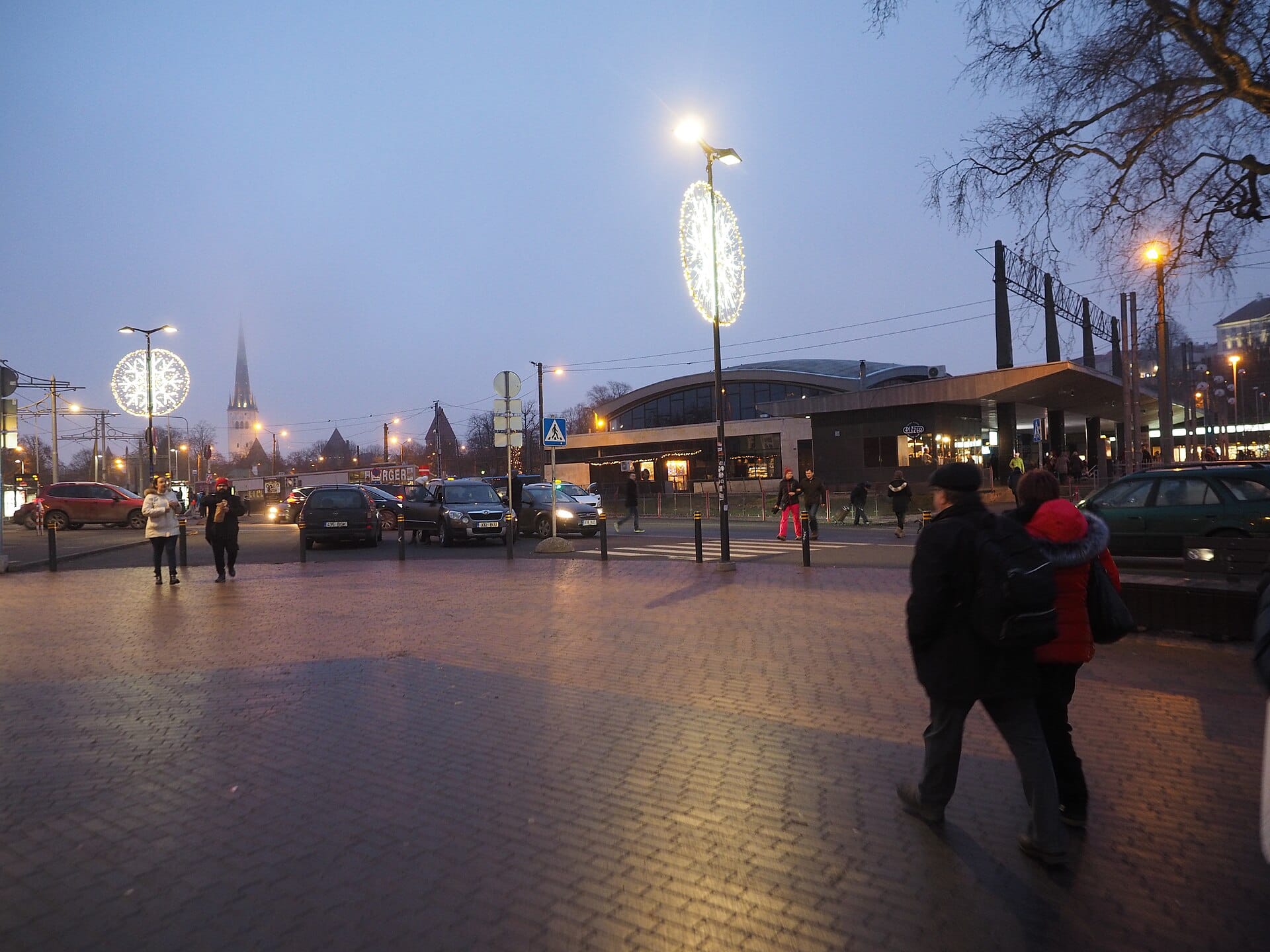 Balti Jaam station and market area in Tallinn at dusk with festive lights and St Olaf's spire in the distance