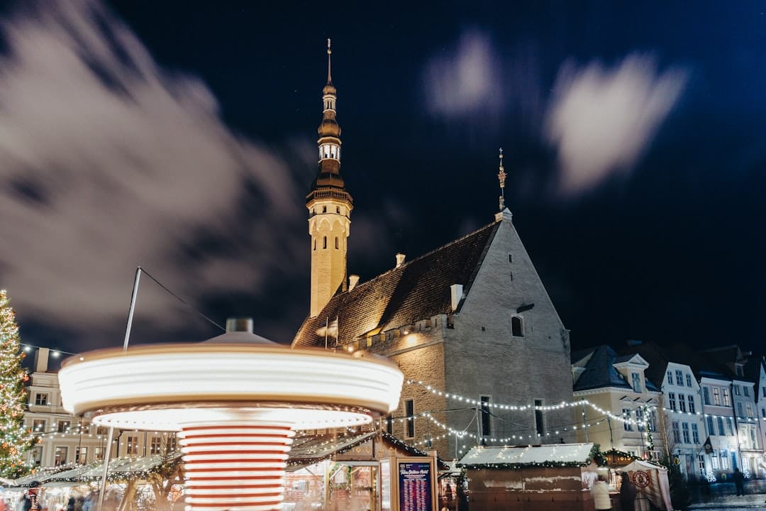 Tallinn Town Hall Gothic tower rising over the Christmas market carousel on Raekoja plats at night