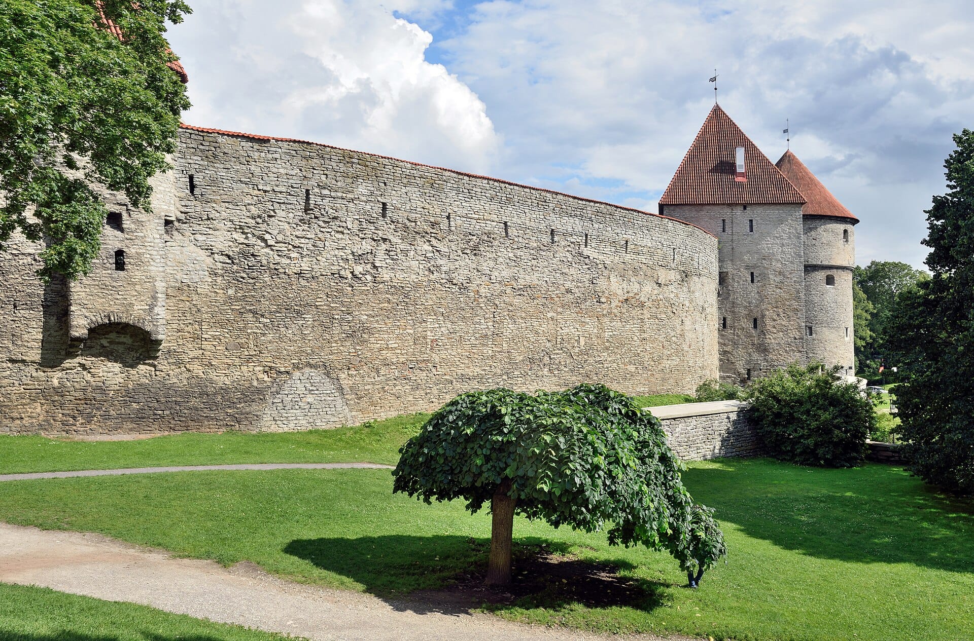 Tallinn's medieval limestone city wall and red-roofed defensive towers in summer