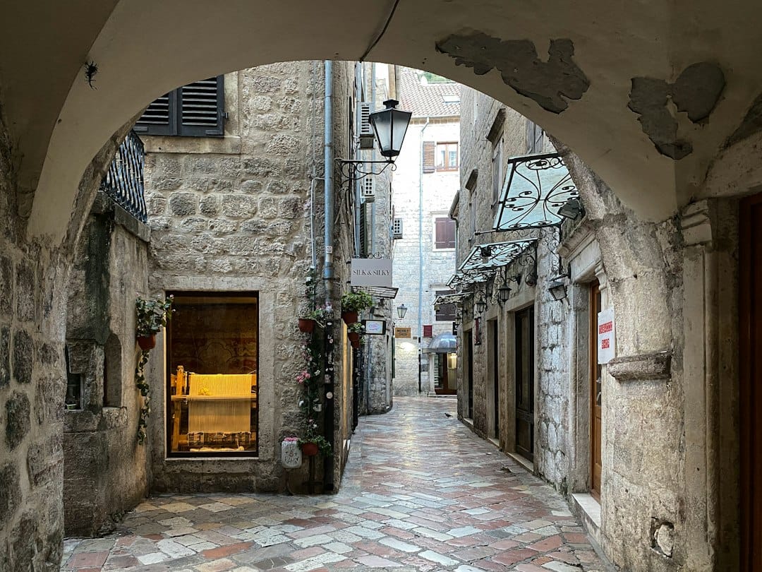 A narrow cobbled stone alleyway in Kotor's Old Town lined with shuttered Venetian-era buildings