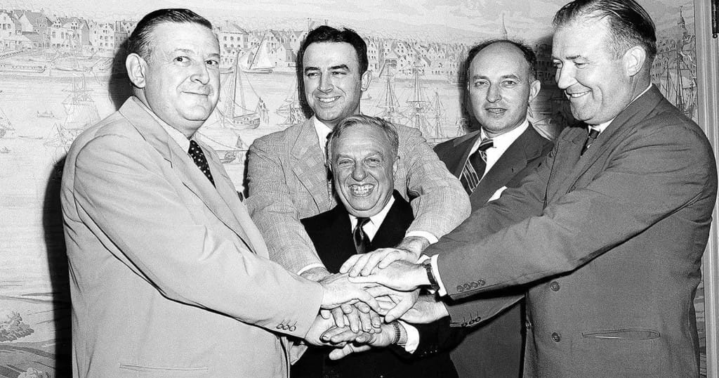 De gauche à droite, Ike Duffey, le vice-président de la NBL Leo Ferris, Ned Irish des New York Knicks et Walter Brown des Celtics de Boston. Au centre de l’image se trouve le commissaire de la NBA, Maurice Podolloff.