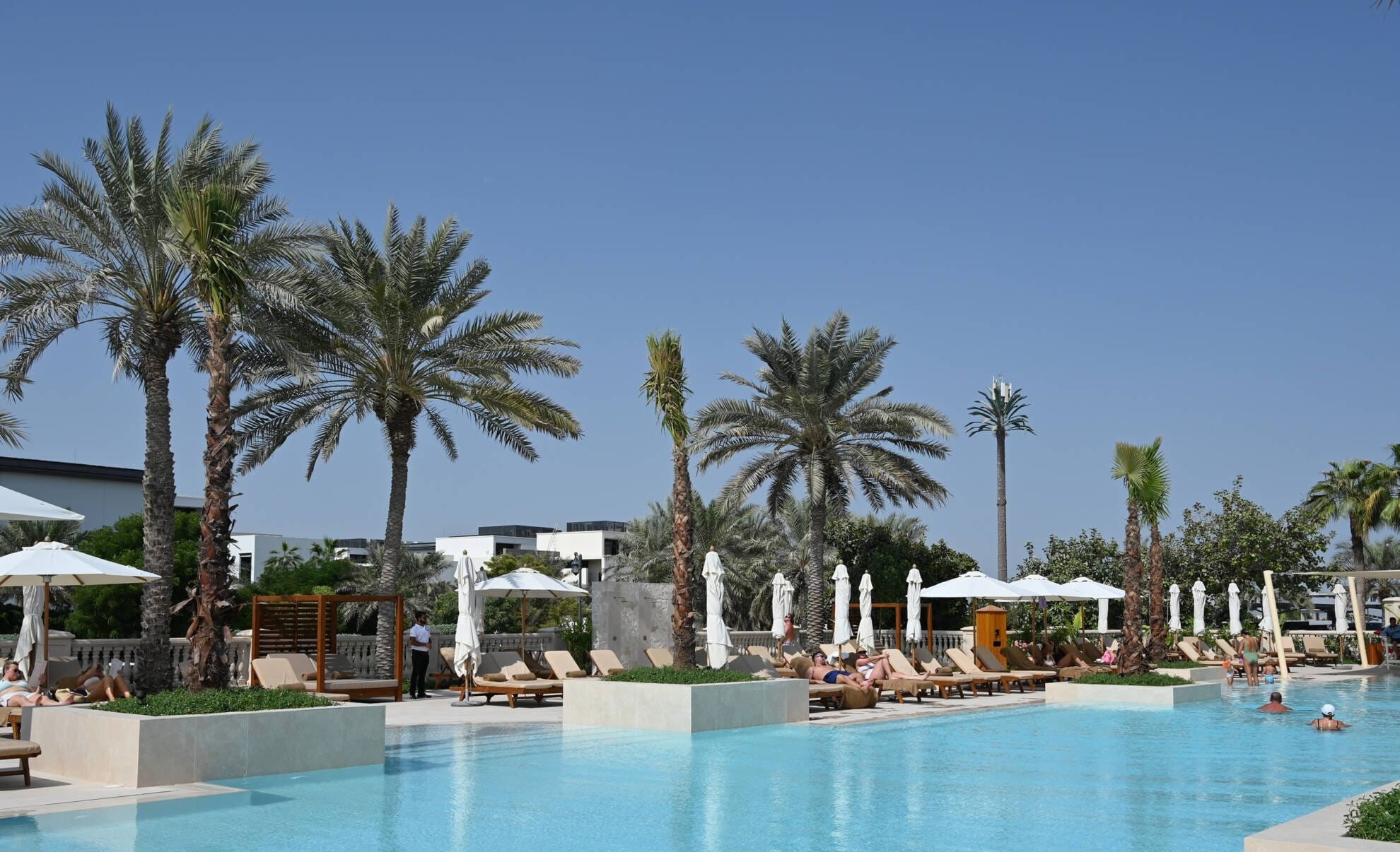 Jumeirah Golf Estates Country Club pool with palm trees and loungers, JGE leisure facility