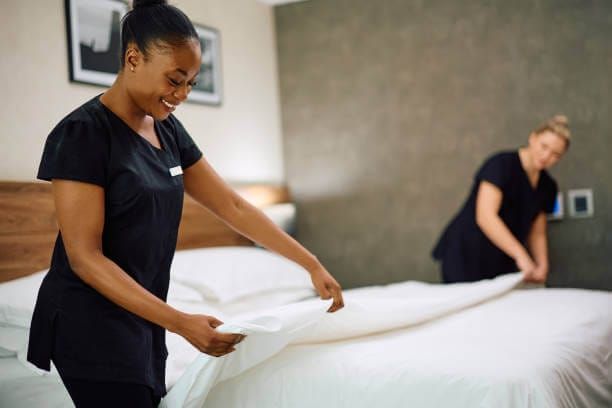 Two housekeepers making a bed, representing the household work that domestic help arrangements in Dubai typically involve