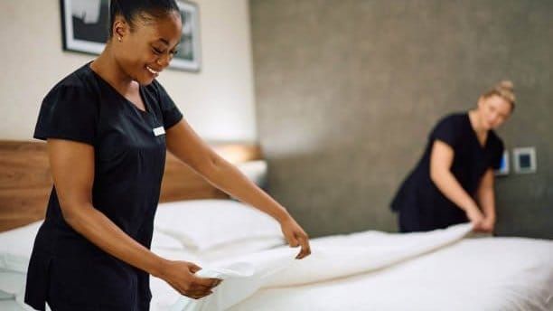 Two housekeepers making a bed, representing the household work that domestic help arrangements in Dubai typically involve