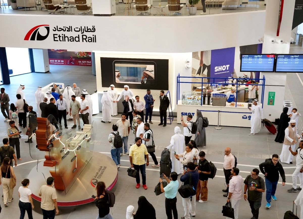 The concourse of an Etihad Rail passenger station, with passengers and the Etihad Rail sign