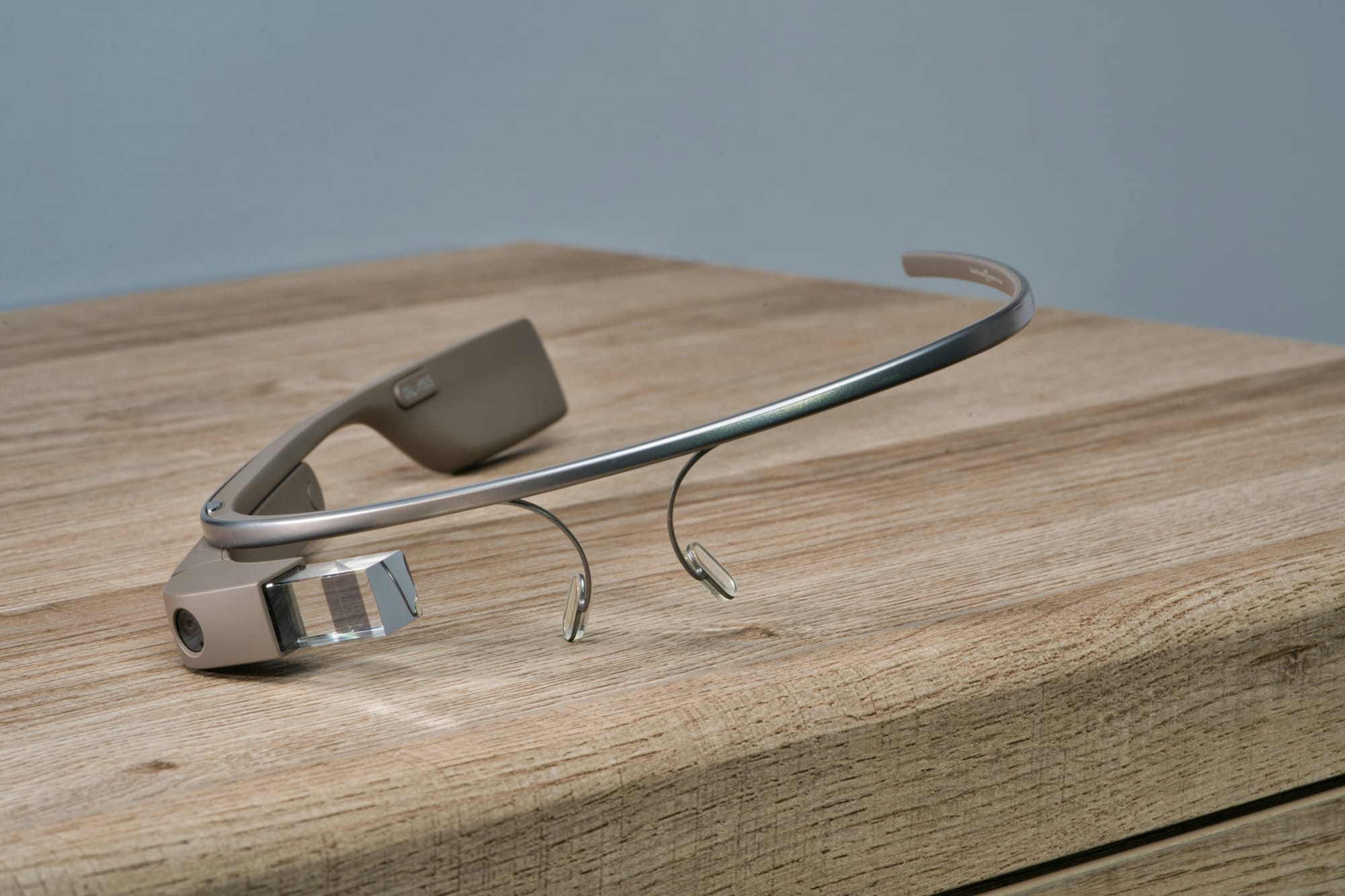 A Google Glass headset on a wooden table, its small camera and clear prism display visible