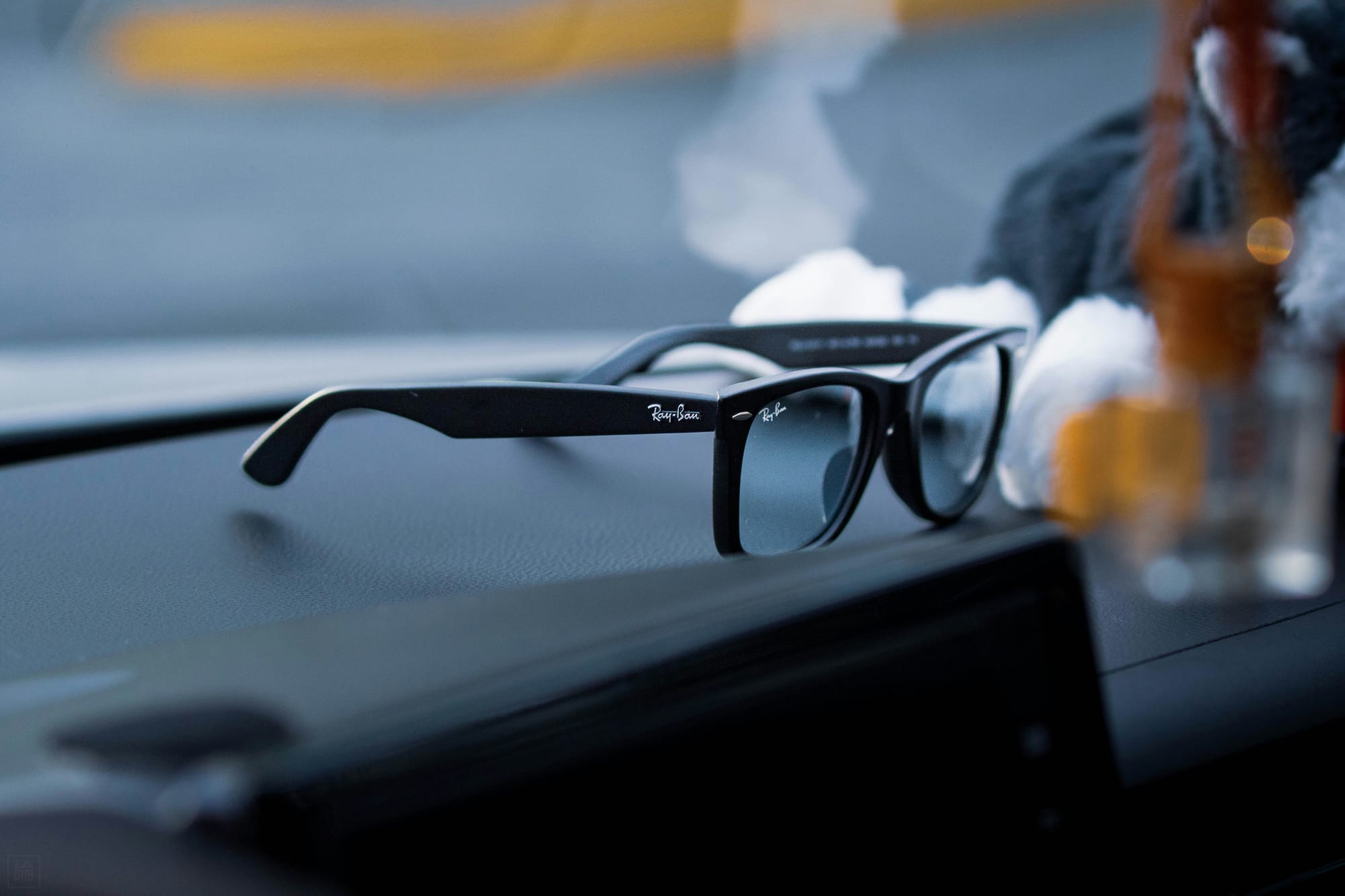 A pair of black Ray-Ban sunglasses resting on a car dashboard