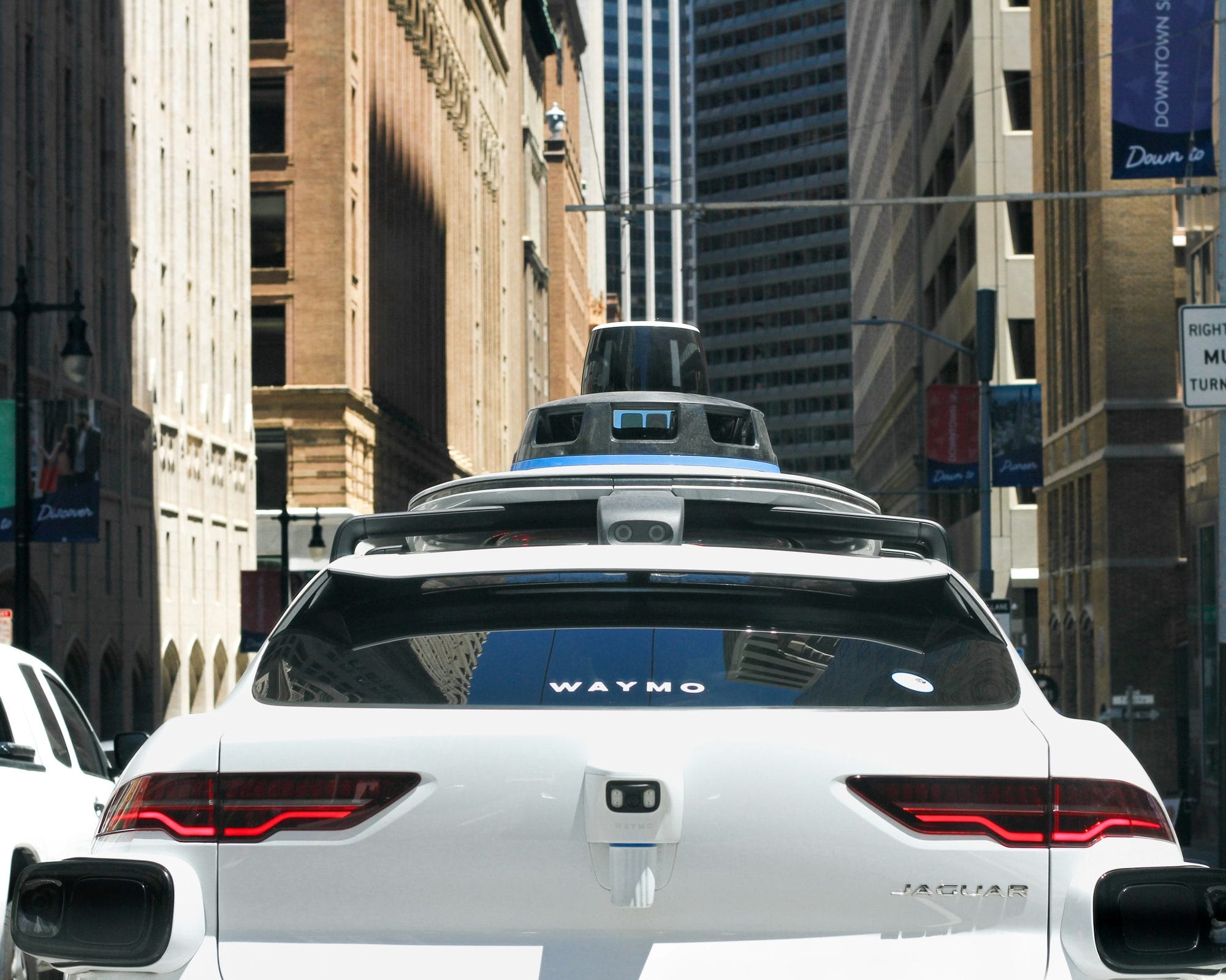 A driverless Waymo Jaguar I-Pace on a downtown street