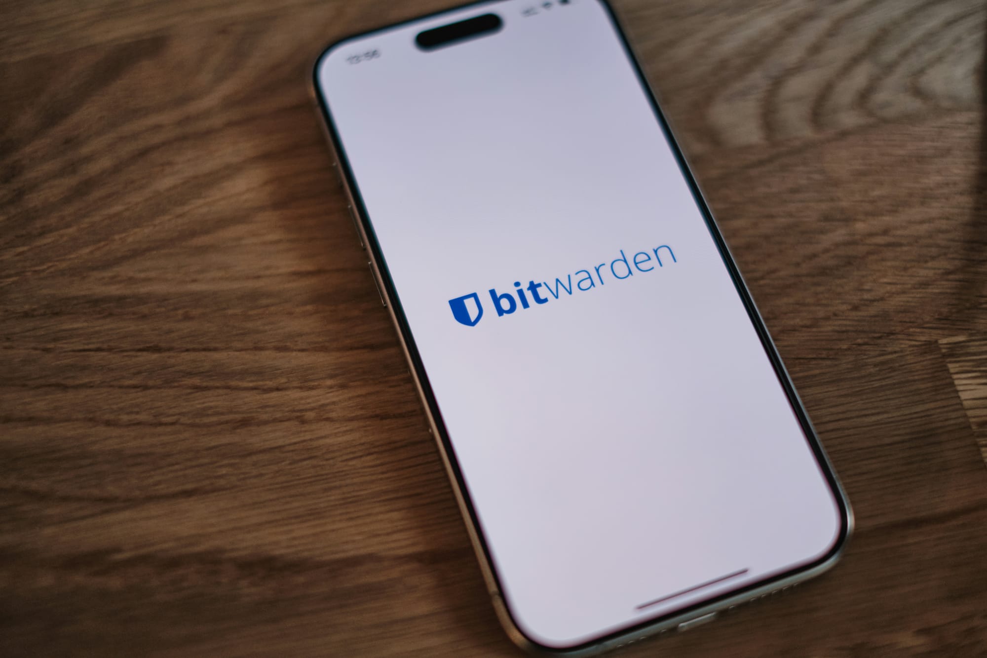 A smartphone on a wooden desk showing the Bitwarden password manager app.