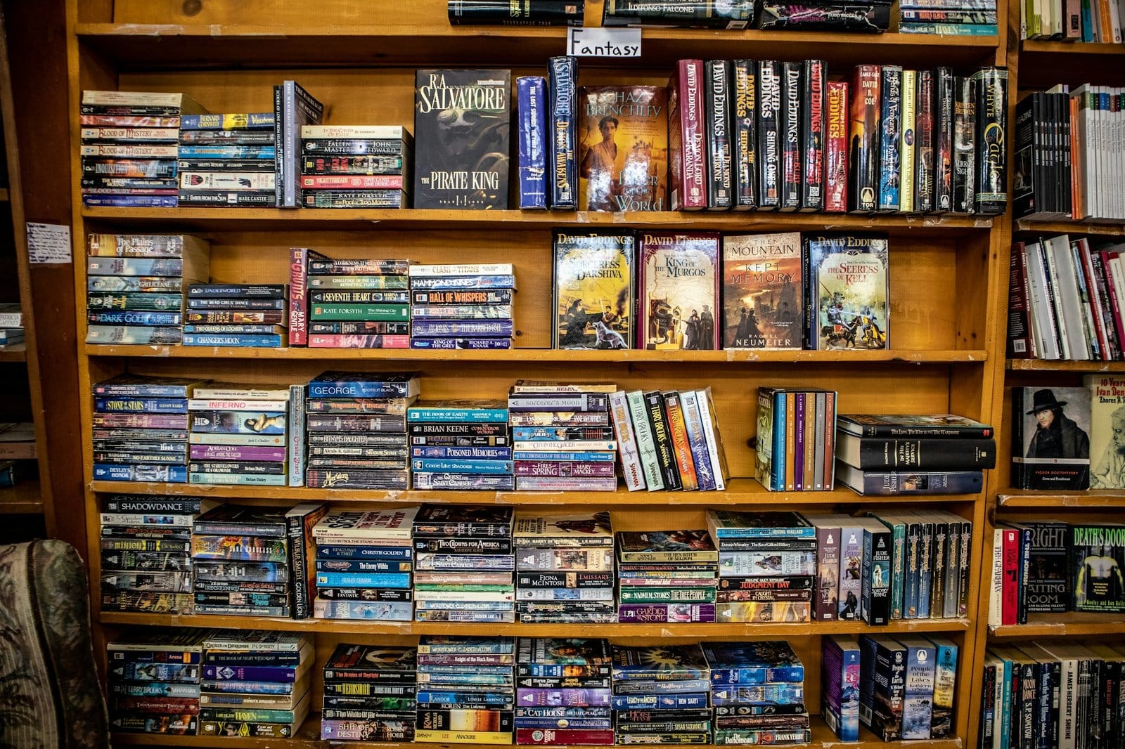 Crowded shelves of used fantasy paperbacks in a secondhand bookstore