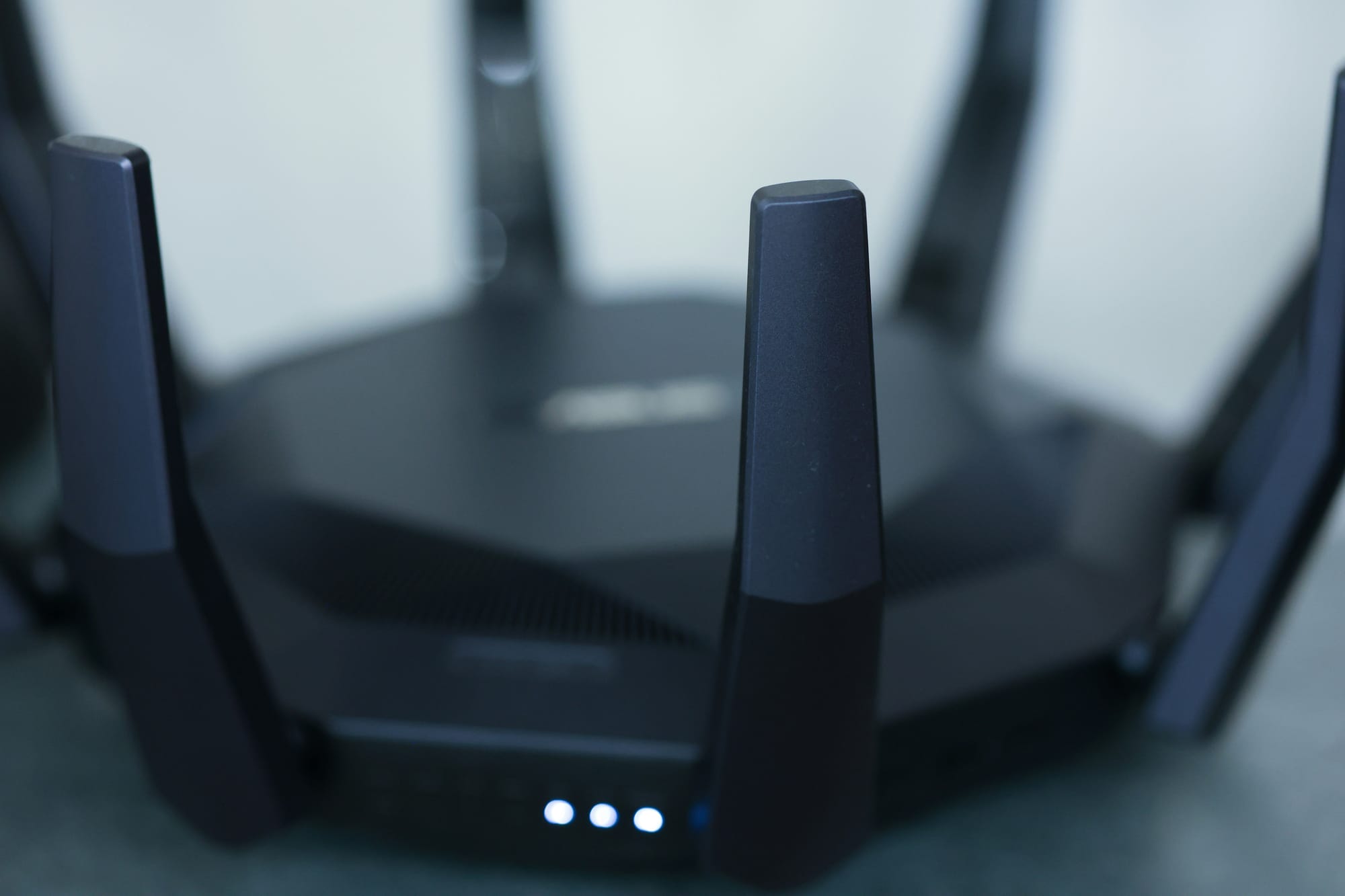 Close-up of a modern black Wi-Fi router with several antennas and blue status lights.