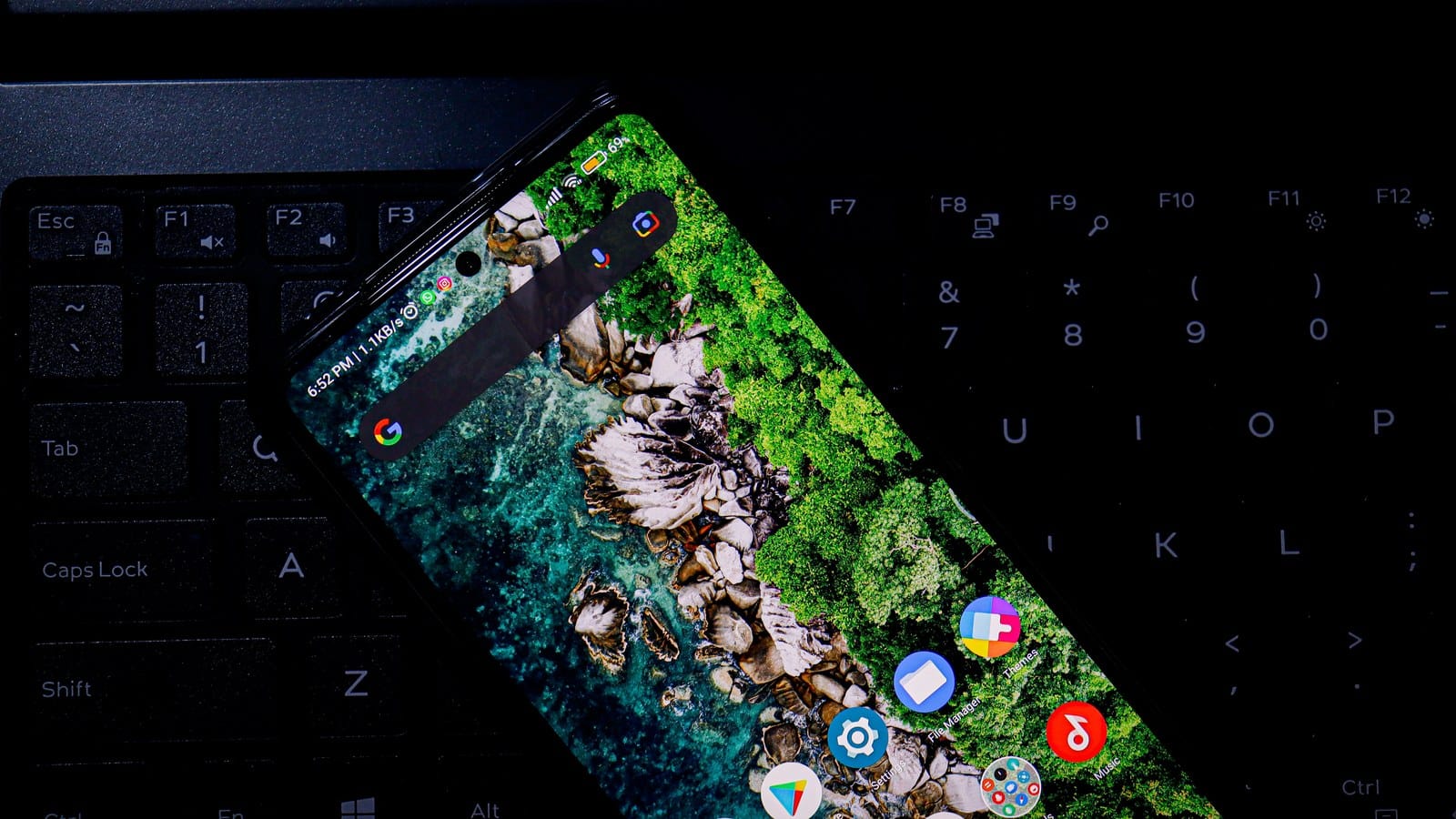 A smartphone resting on a laptop keyboard.