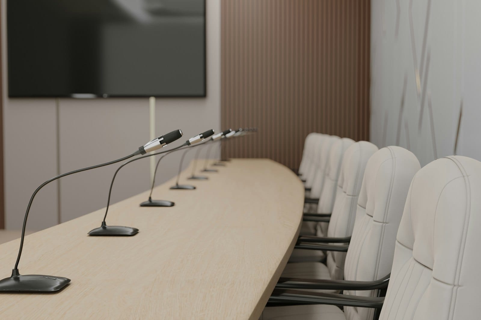 An empty meeting room with microphones and chairs along a long table
