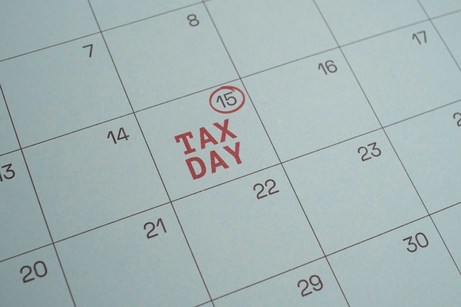 Closeup of a calendar page with Tax Day printed in red under a circled 15.
