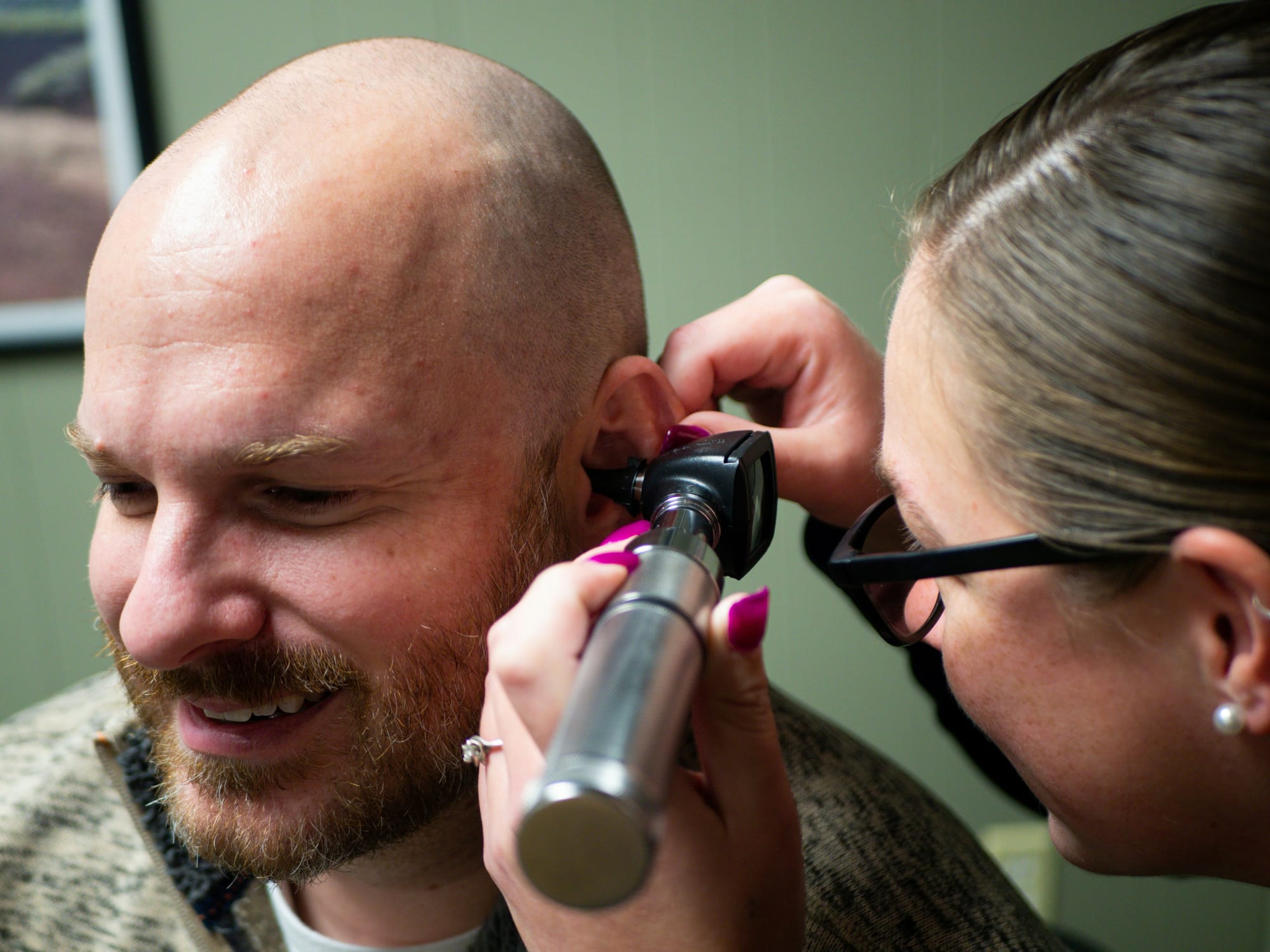 A clinician examining a patient's ear with an otoscope.