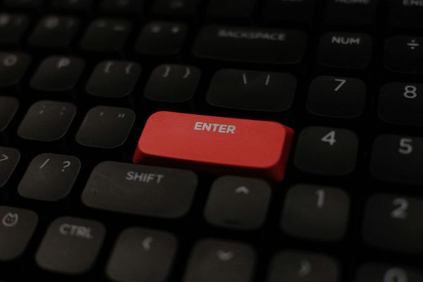 A close-up of a red Enter key on a dark keyboard.