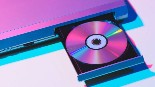 A disc ejecting from a slot-loading player under pink and blue light