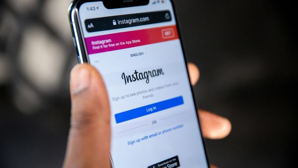 A hand holding a smartphone with the Instagram app open on screen.
