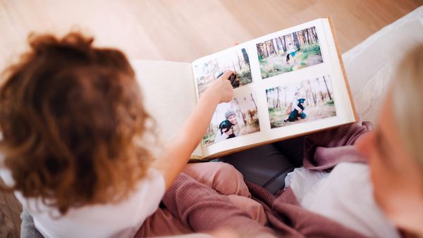 A child and an adult flipping through a printed photo album together.