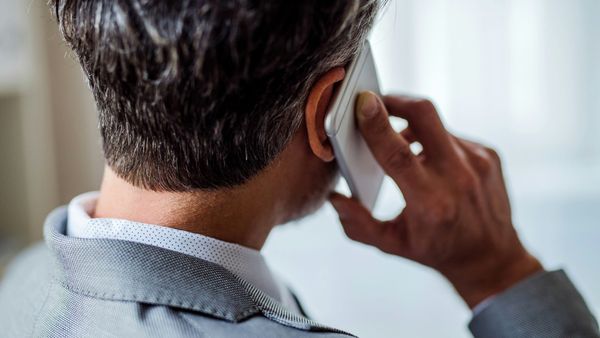 A man photographed from behind, holding a phone to his ear