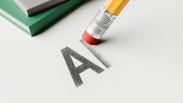 A pencil eraser rubbing out the letters A and I written in pencil, with the I half erased and smearing rather than coming clean, beside a stack of books