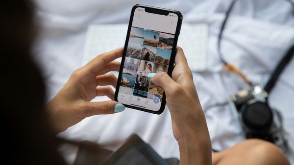 Two hands holding a smartphone showing a grid of photos