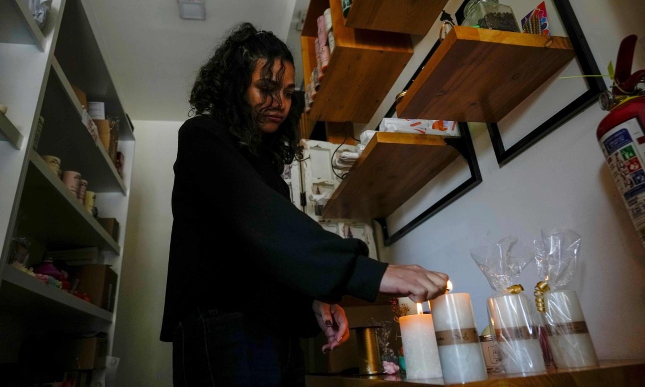 A woman lights candles in her store during a power cut in Quito, Ecuador. Photo: Dolores Ochoa/AP
