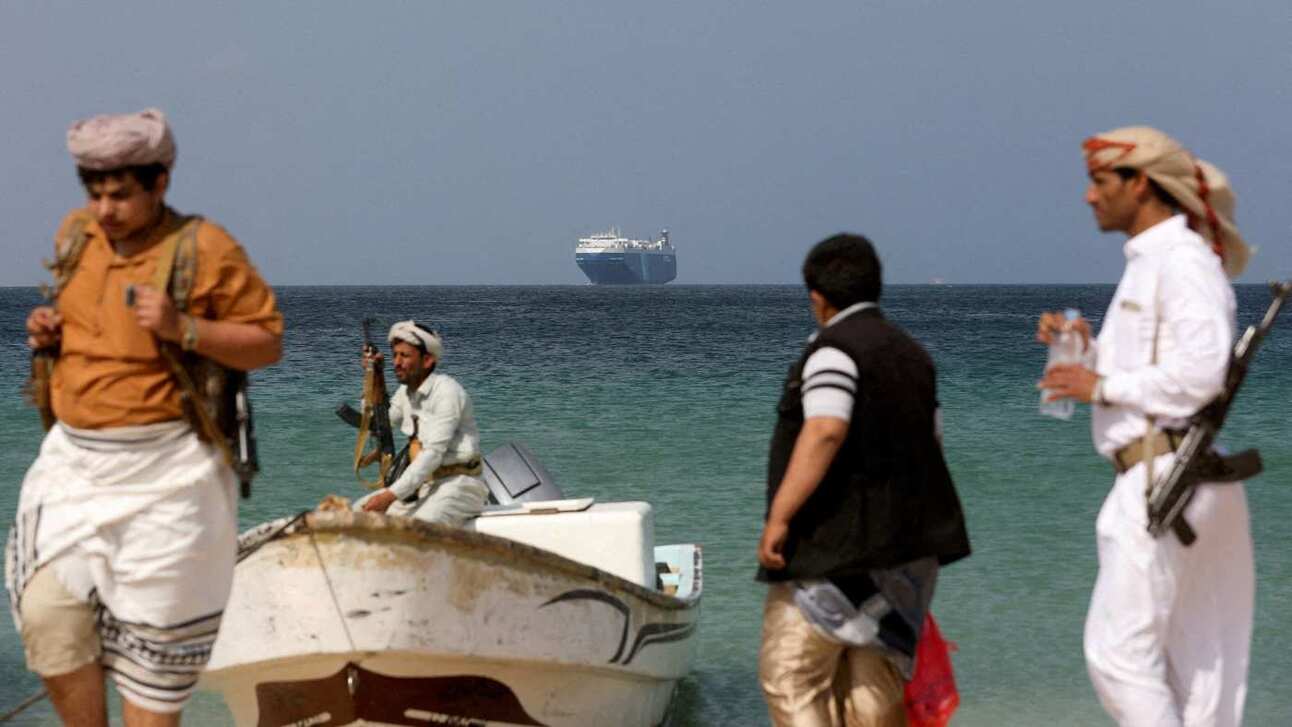 Armed men stand on a beach as a commercial ship, seized by the Houthis last month, is anchored off the coast of Yemen. Photo: Reuters