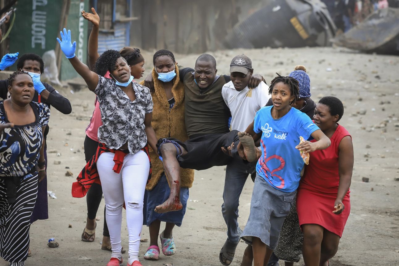 Residents help a man allegedly hit in the leg by a stray bullet as he sat near his house during clashes between police and protesters in Nairobi. Photo: AP