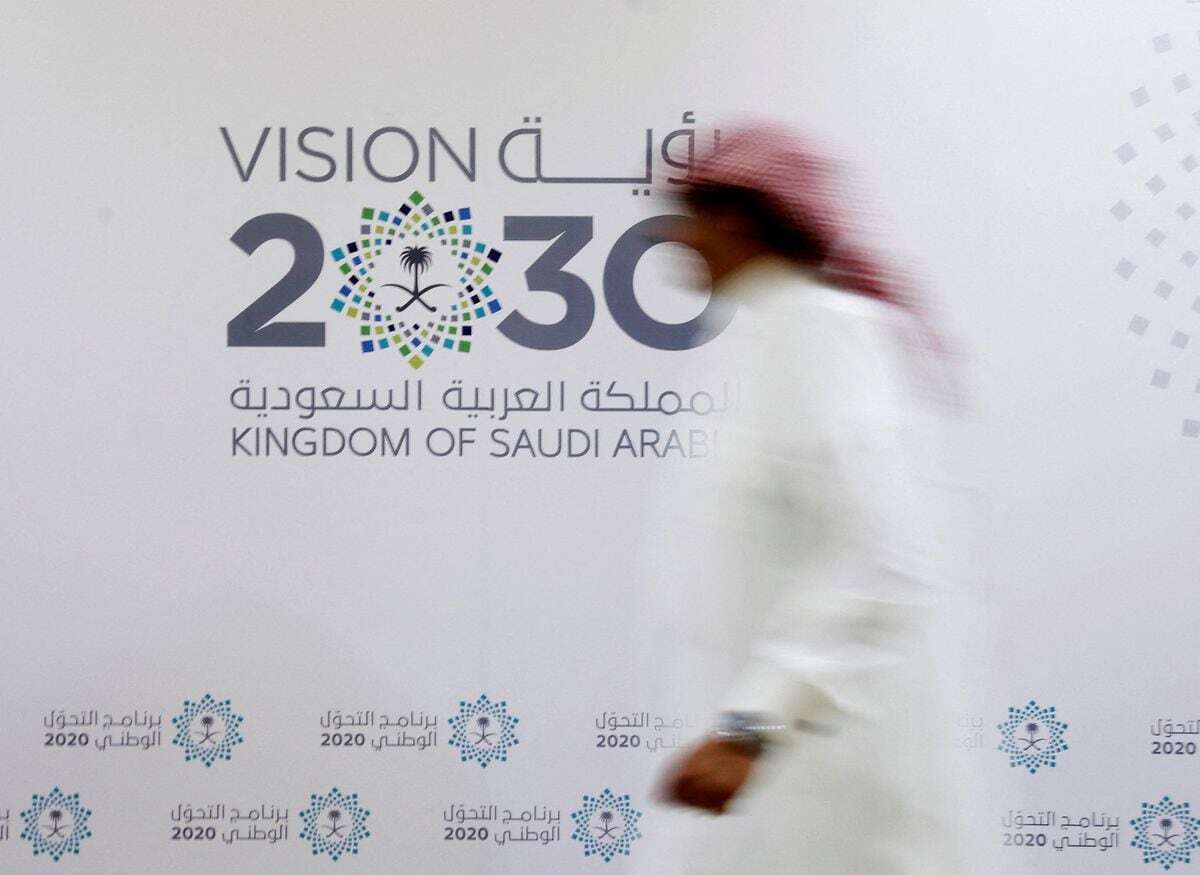 A Saudi man walks past the logo of Vision 2030 at a conference in Jeddah. File photo: Faisal Al Nasser/Reuters