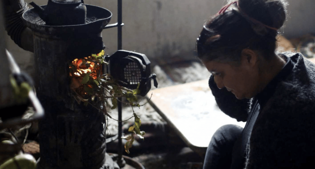 A woman uses a wood-fired heater at her home in Damascus, Syria. Photo: Yamam al Shaar/Reuters