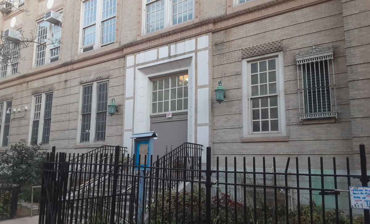 The facade and front door of a stately brick school building in New York City. 