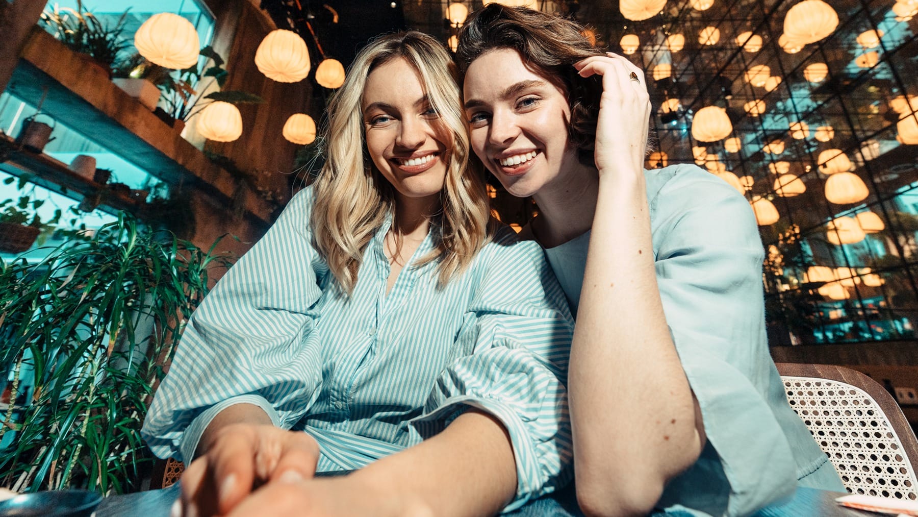 Zwei Frauen sitzen in einem Restaurant mit warm beleuchtetem Hintergrund