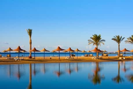 Poolanlage mit Palmen und Sonnenschirmen vor dem Meer in Ägypten