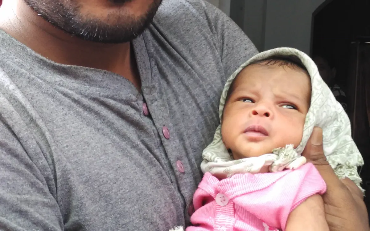 Ein Vater hält sein neugeborenes Kind behutsam im Arm